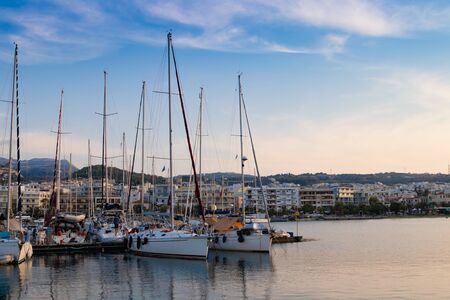 Beautiful cityscape port, arsenal, modern buildings, yachts, azure sea water on the background of stormy sky at evening, harbour of Rethymno, island of Crete, Greece, Southern Europe.の写真素材