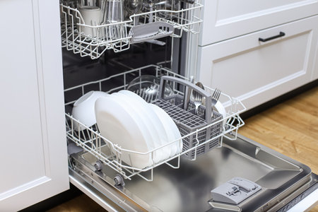 Open dishwasher with clean dishes in a white kitchen.Kitchen with integrated appliancesの写真素材