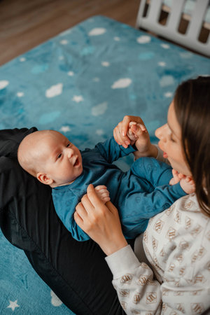 A young mother plays with her newborn son on the bed at home. Concept motherhoodの写真素材