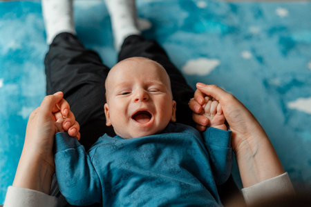Newborn baby boy lying on his mother's lap and laughing.の写真素材