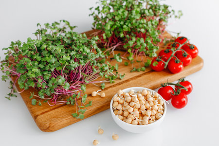 Fresh microgreens with chickpeas and tomatoes on cutting boardの写真素材