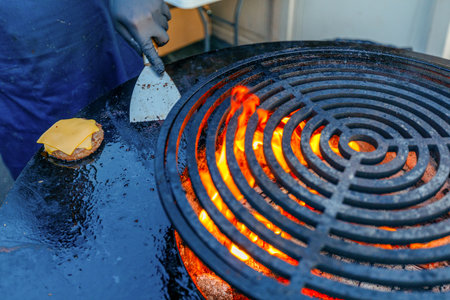 Chef cooking a hamburger on a barbecue grill in a restaurantの写真素材