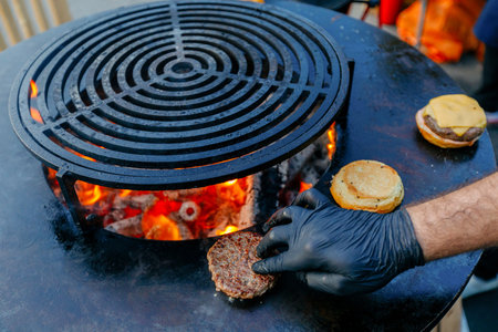 Chef cooking hamburger on barbecue grill, close-up.の写真素材