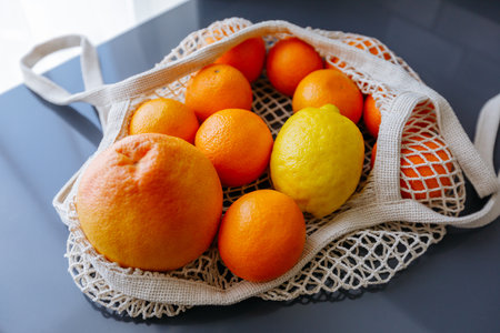 Citrus fruits in a beautiful trendy cotton string bag on the kitchen table, eco-friendly packaging, zero waste.の写真素材