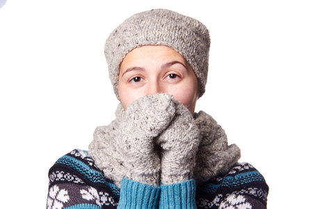 Young beautiful girl is breathing on his gloved hands. Portrait on a white background