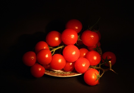 Cherry tomatoes on a branch on a black background  Photo taken in the dark with a light brush の写真素材