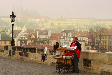 Prague, Czech Republic - November 14, 2012  racy old organ grinder on the Charles Bridge on the background of the magnificent medieval Prague , Czech Republic - November 14, 2012のeditorial素材
