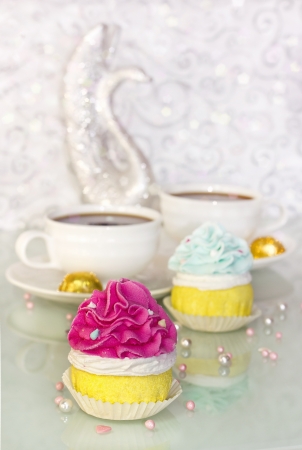 pink and blue cupcakes with two cup of coffee on blurred backgroundの写真素材