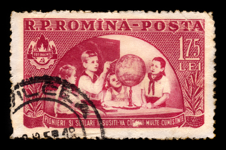 ROMANIA - CIRCA 1954: A stamp printed in Romania shows young pioneers looking at a globe, circa 1954のeditorial素材