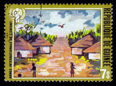 Guinea - CIRCA 1980: stamp printed in Guinea shows children in african village, series year of the child, circa 1980のeditorial素材