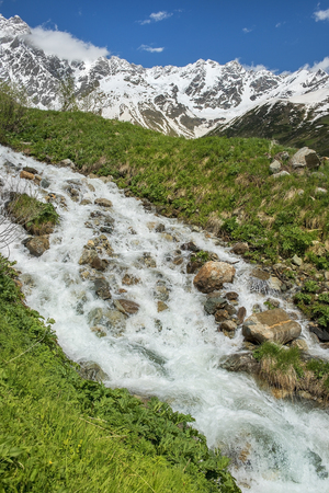 rough mountain stream and snow-capped peaks of the Caucasus Mountains in Upper Svaneti, Greater Caucasus Mountain Range in Georgiaの写真素材