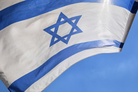 Star of David on a blue and white israeli flag against a bright skyの写真素材