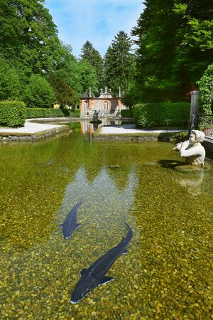 Salzburg, Austria - May 25, 2019 : sculptures at the pond in Public Gardens of Hellbrunn Palace (Schloss Hellbrunn) in Salzburg. in the foreground large sturgeonのeditorial素材