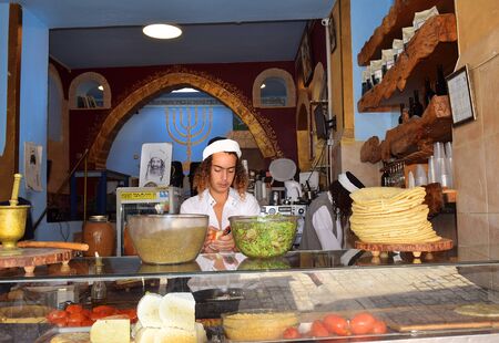 Safed, Upper Galilee, Israel - July 19, 2019: young sephardic religious jew, working as a cook in a kosher cafe in the quarter of artists in the old town of Safedのeditorial素材