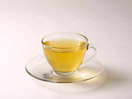 Green tea served hot in an transparent cup and saucer on a white backgroundの写真素材