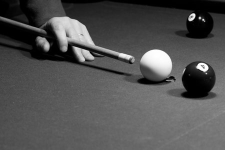 Man is aiming the billiard shot - cue is in his hand, and the balls are on the table.Picture was...