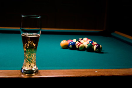Glass of refreshing beer on the billiard table with the racked billiard balls