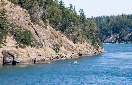 Small boat leaving the rocky coastline. Gulf Islands. British Columbia.の写真素材