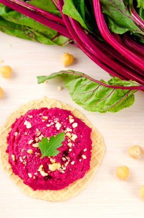 Beet hummus with peanuts and parsley on thin wafers.の写真素材