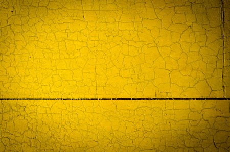 Wall painted in yellow, cracked. Abstract backgroundの写真素材