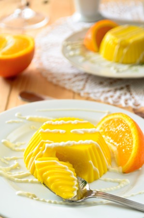 custard pudding with vanilla sauce and orange on wooden backgroundの写真素材