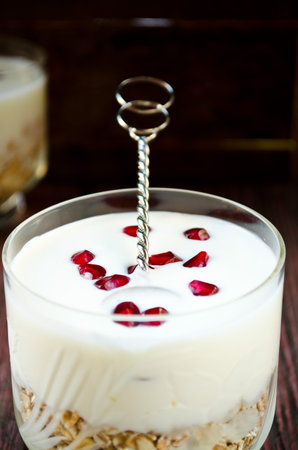 Healhty breakfast with oatmeal, greek yogurt and pomegranate berries on wooden table