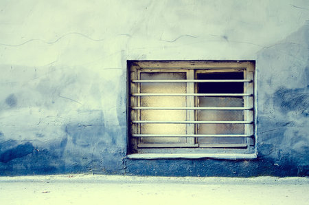 Dirty old window with bars on a grungy building.