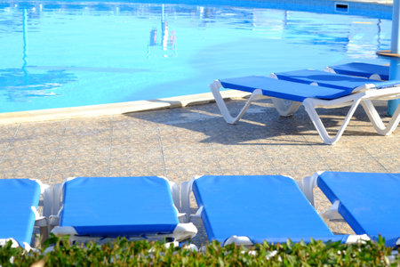 Blue beach chairs and sun umbrella near pool. Travel background.