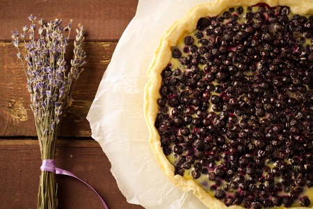 Bilberry, blueberry tart with lavender on white plate, wooden background, vintage style, tonedの写真素材