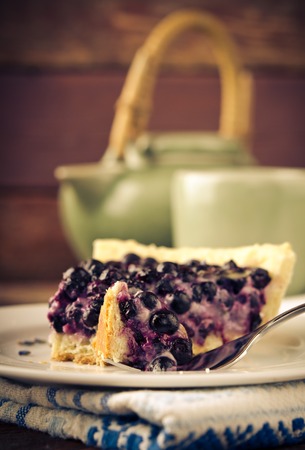 Bilberry, blueberry tart with lavender on white plate, wooden background, vintage style, tonedの写真素材