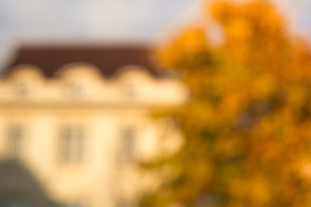 Blurred fall trees and house facade, festive background autumn nature.の写真素材