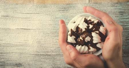 Man hands holding Cup of hot chocolate with marshmallows on snowy wooden table, Christmas, New Year, Winter backgroundの写真素材