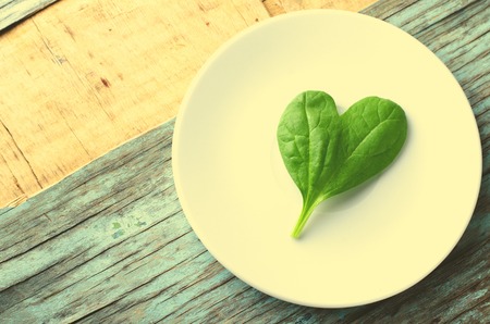 Fresh Baby spinach heart shape leaf on white plate, blue wooden background. Top view with copy space. Love, Healthy, Ecology conceptの写真素材