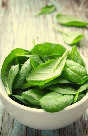 Fresh Baby spinach leaves in white bowl on blue wooden background. Top view with copy space, horizontal. Healthy, Ecology conceptの写真素材
