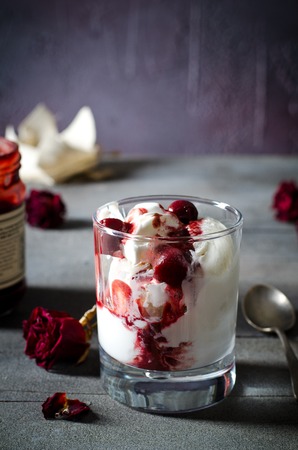 Sundae Ice cream with cherry in chocolate topping, and dried rose flowers on dark background. Love, Valentines day concept. Copy spaceの写真素材