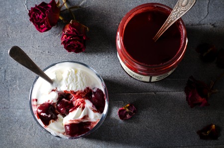 Sundae Ice cream with cherry in chocolate topping, and dried rose flowers on dark background. Love, Valentines day concept. Copy spaceの写真素材