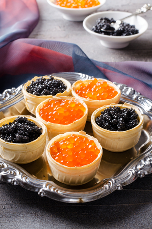 Black and red caviar tartlets, appetizer canapes on silver trayの写真素材