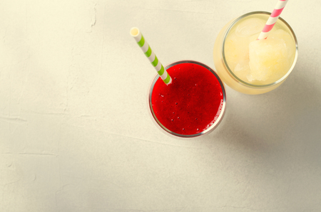 Strawberry smoothies and ice lemonade with cocktail tubes in glasses, on white background.の写真素材