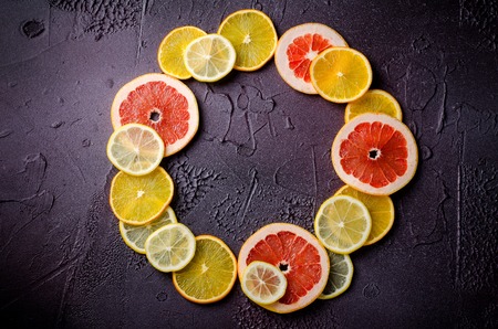 Citrus fruit slices of lemon, orange, grapefruit in circle shape on dark background., horizontal, top viewの写真素材