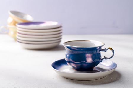Empty colorful porcelain tableware. Blue cup with plate on lilac backgroundの写真素材