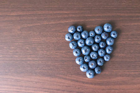 Blueberries laid out on a wooden board in the form of a heartの写真素材