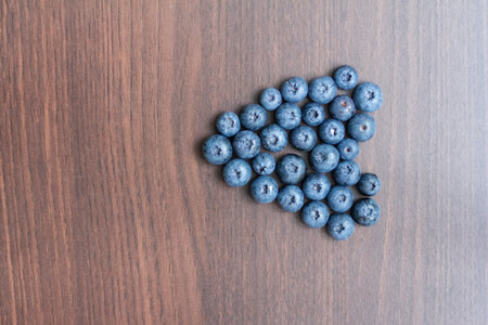 Blueberries laid out on a wooden board in the form of a heart. Space for text. Vertical format....