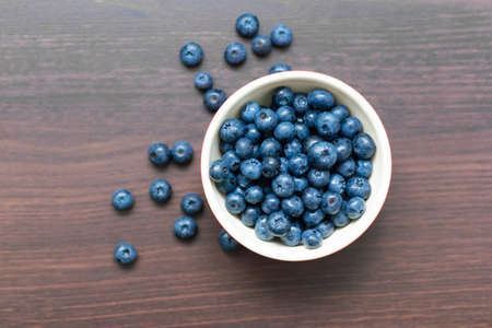 Blueberries in a red bowl on wooden table. Selective focusの写真素材