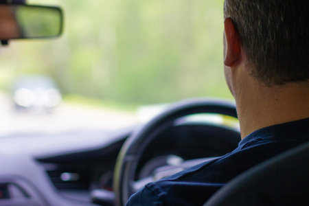 Adult man driving a car. Generic photo of man driving a car through slight turn