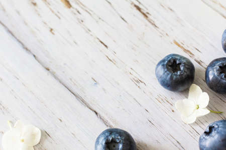 Ripe blueberries, hydrangea flowers nearby. Light wooden backgroundの写真素材