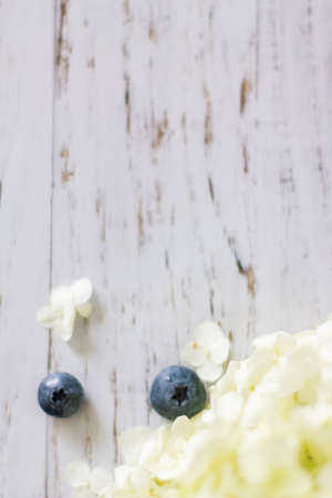 Ripe blueberries. Blueberries are in a vine basket with hydrangea flowers nearby. Light wooden background. close-up. selective focusの写真素材
