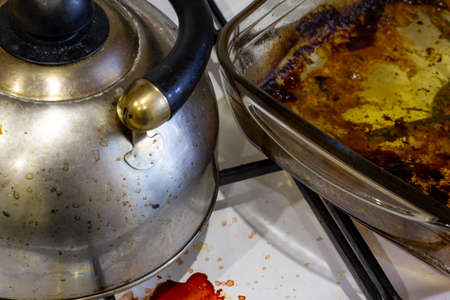 A dirty burner gas stove in the kitchen. Dirty kettle, saucepan, glass baking dish, frying panの写真素材