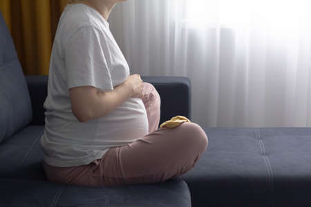 Pregnant woman resting alone at home strokes touches her big bellyの写真素材