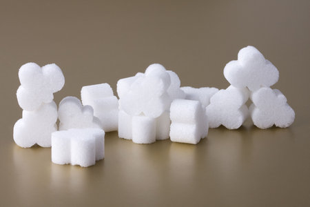 Pile of sugar on gold background. Few pieces of sugar. Some Sugar lumps.