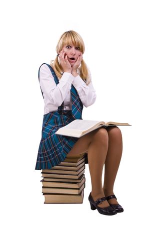 Senior high school student in uniform is sitting on the stack of book and study up. Young and beautiful schoolgirl  is wearing a traditional uniform is shocked by something.の写真素材